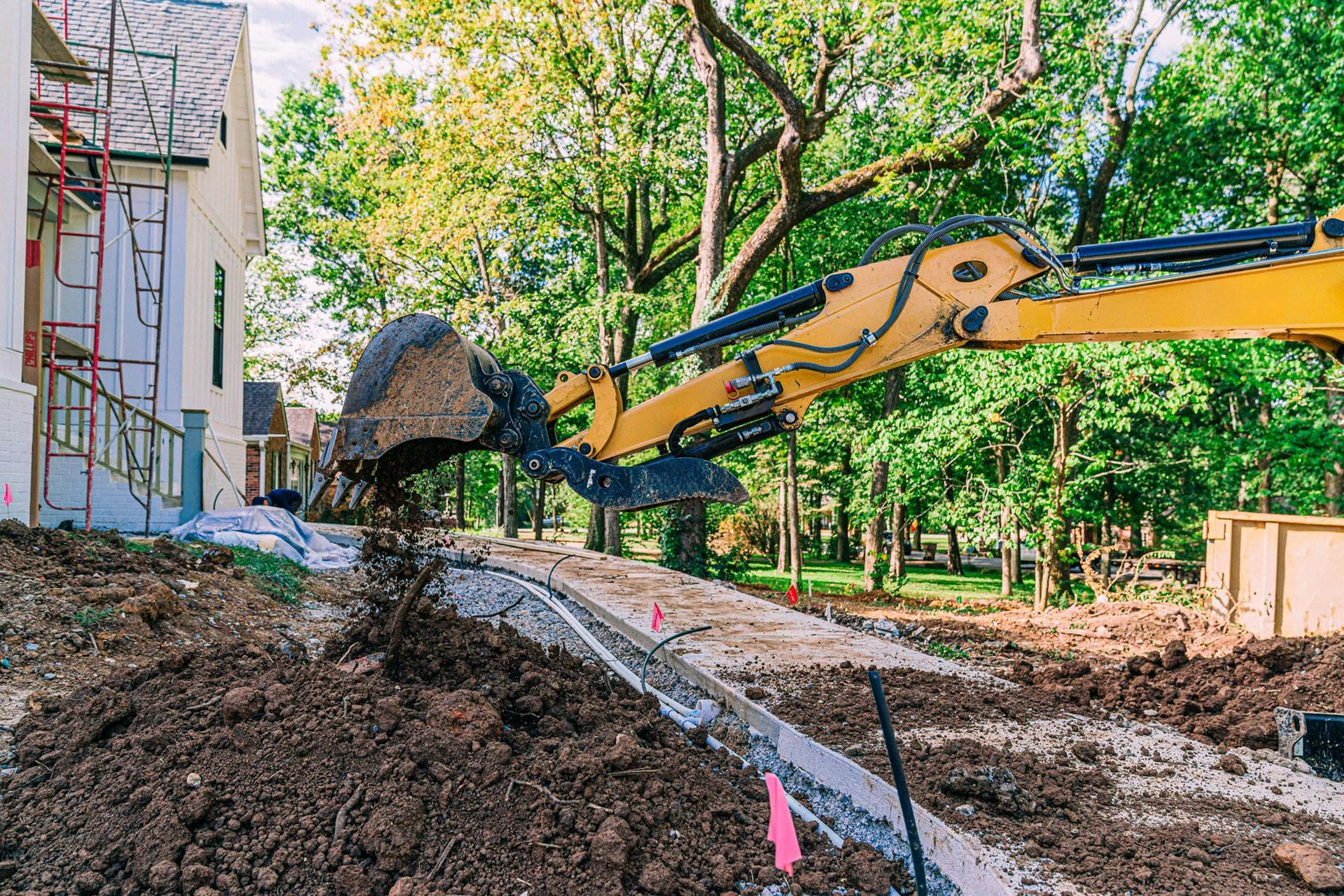 A yellow excavator is digging a hole in the ground at a construction site. Residential Hardscape Services Arlington WA