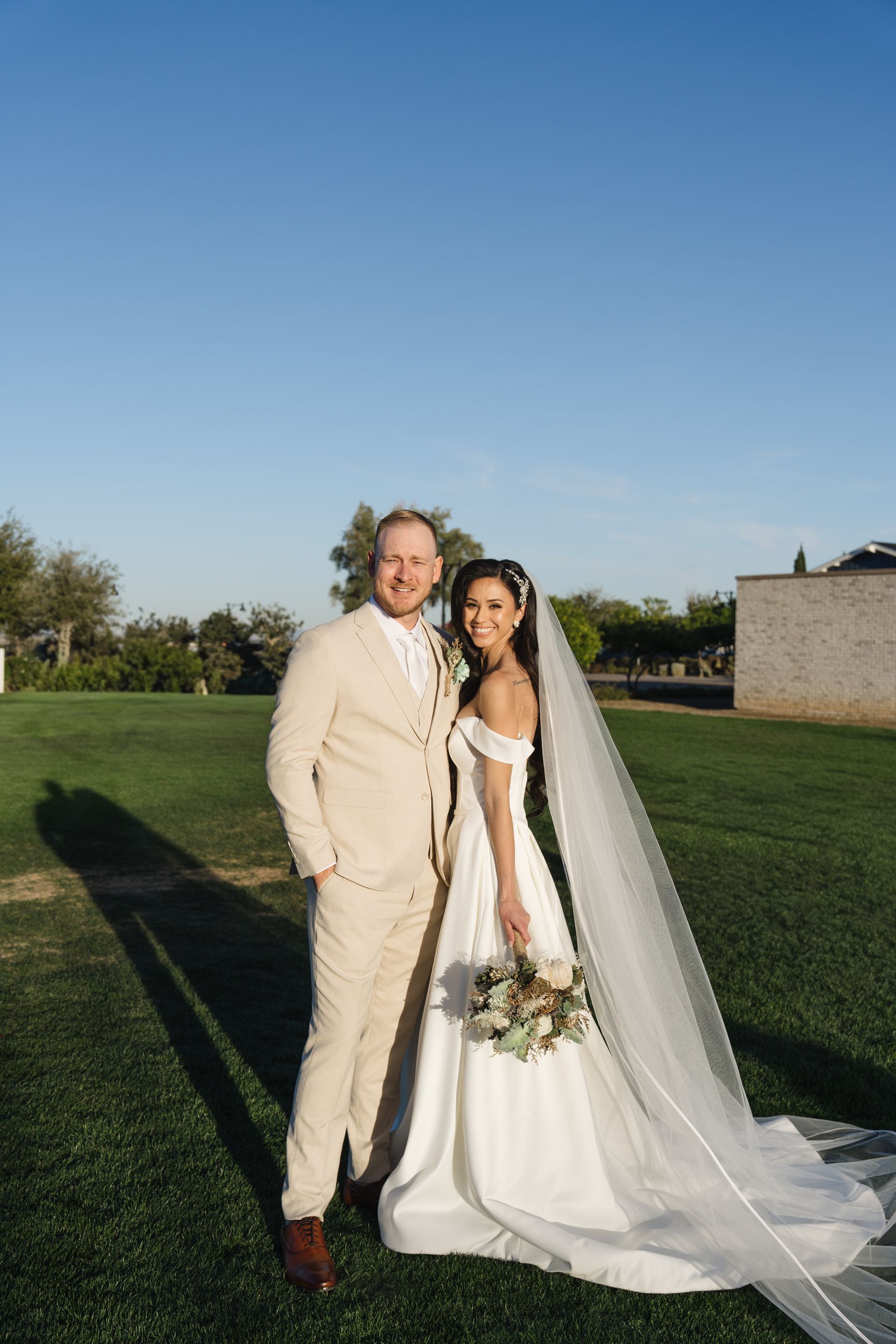 A bride and groom are kissing in front of the sun.