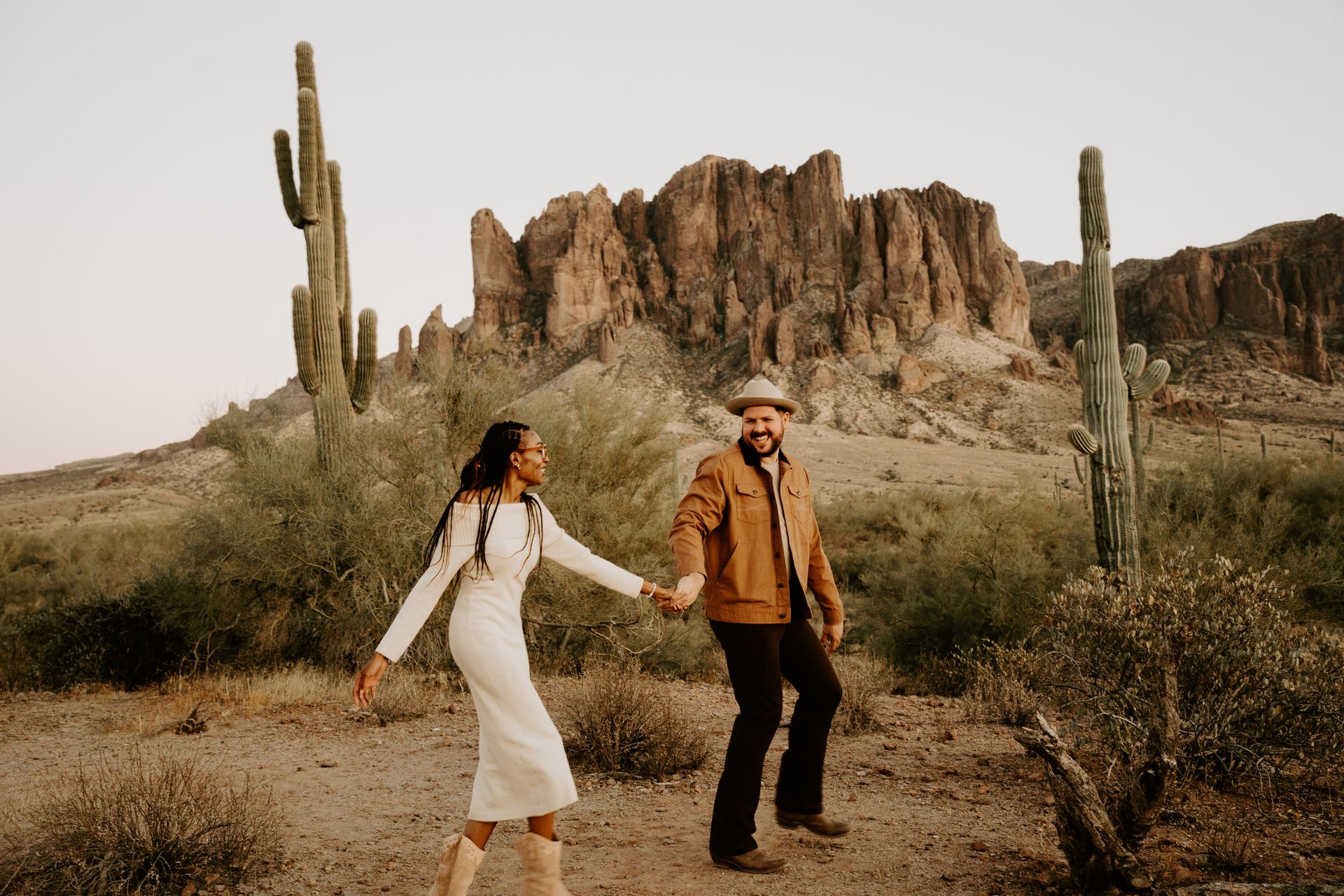A man and a woman are holding hands in the desert.