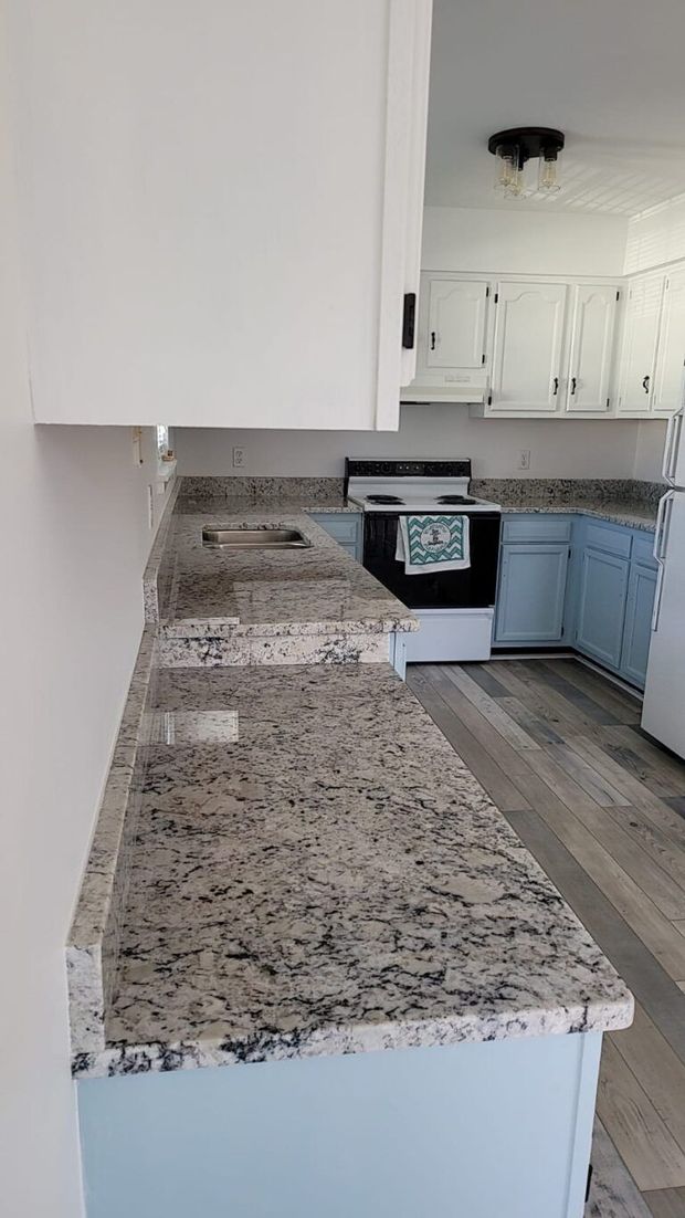 Kitchen with white cabinets, granite countertops, and a black stove in the background.