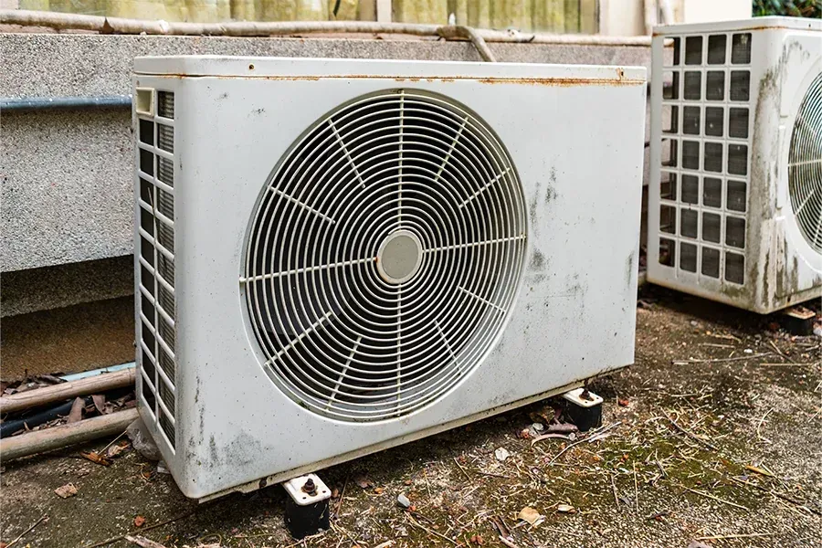 Outdoor HVAC condenser unit with large fan, sitting on a rooftop beside another unit.