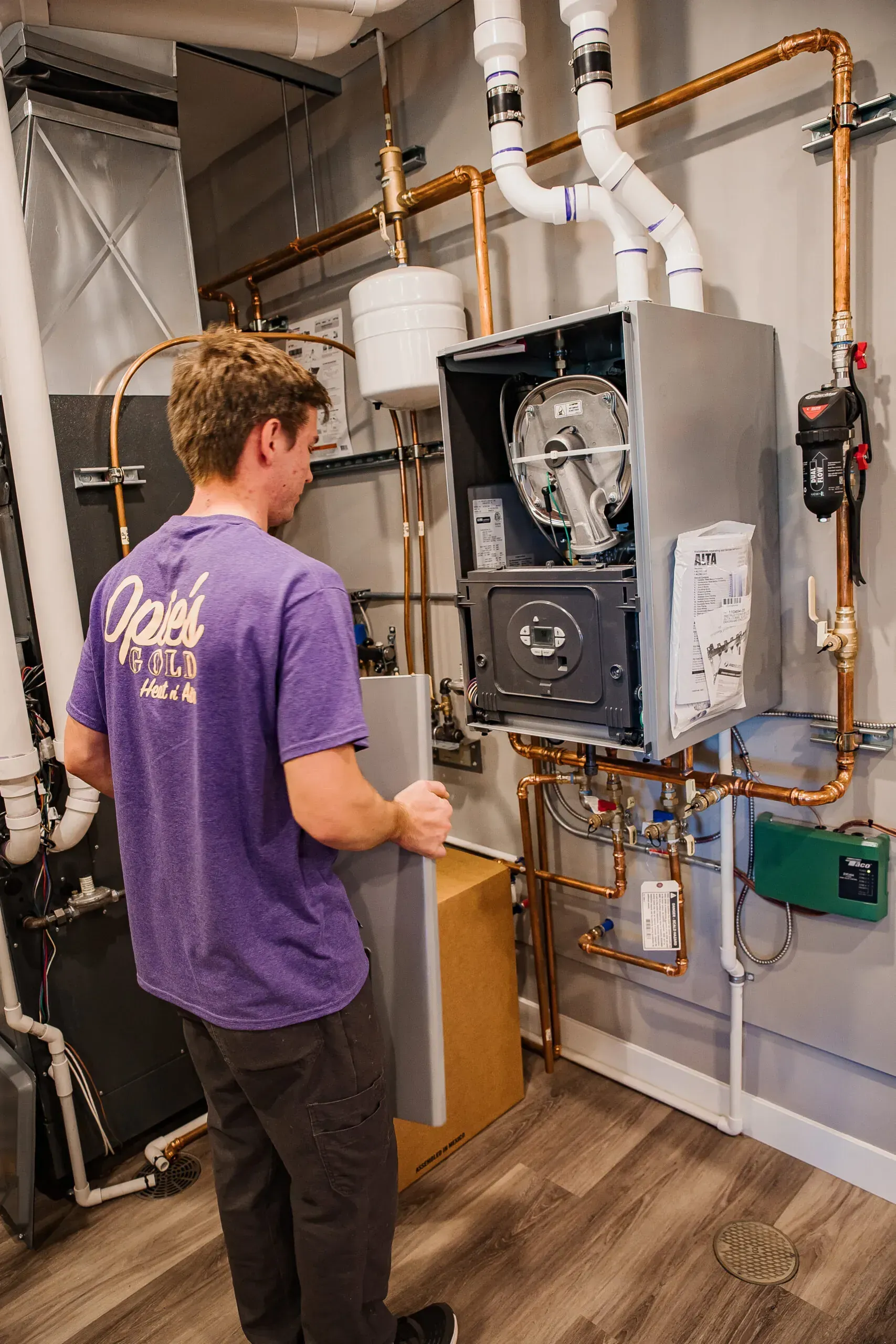 Technician inspecting a wall-mounted furnace and ductwork in a utility room