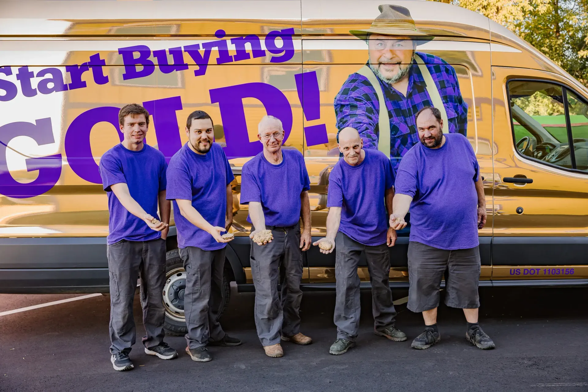 Five men in purple shirts stand in front of a yellow van with “Start Buying Gold!” signage.