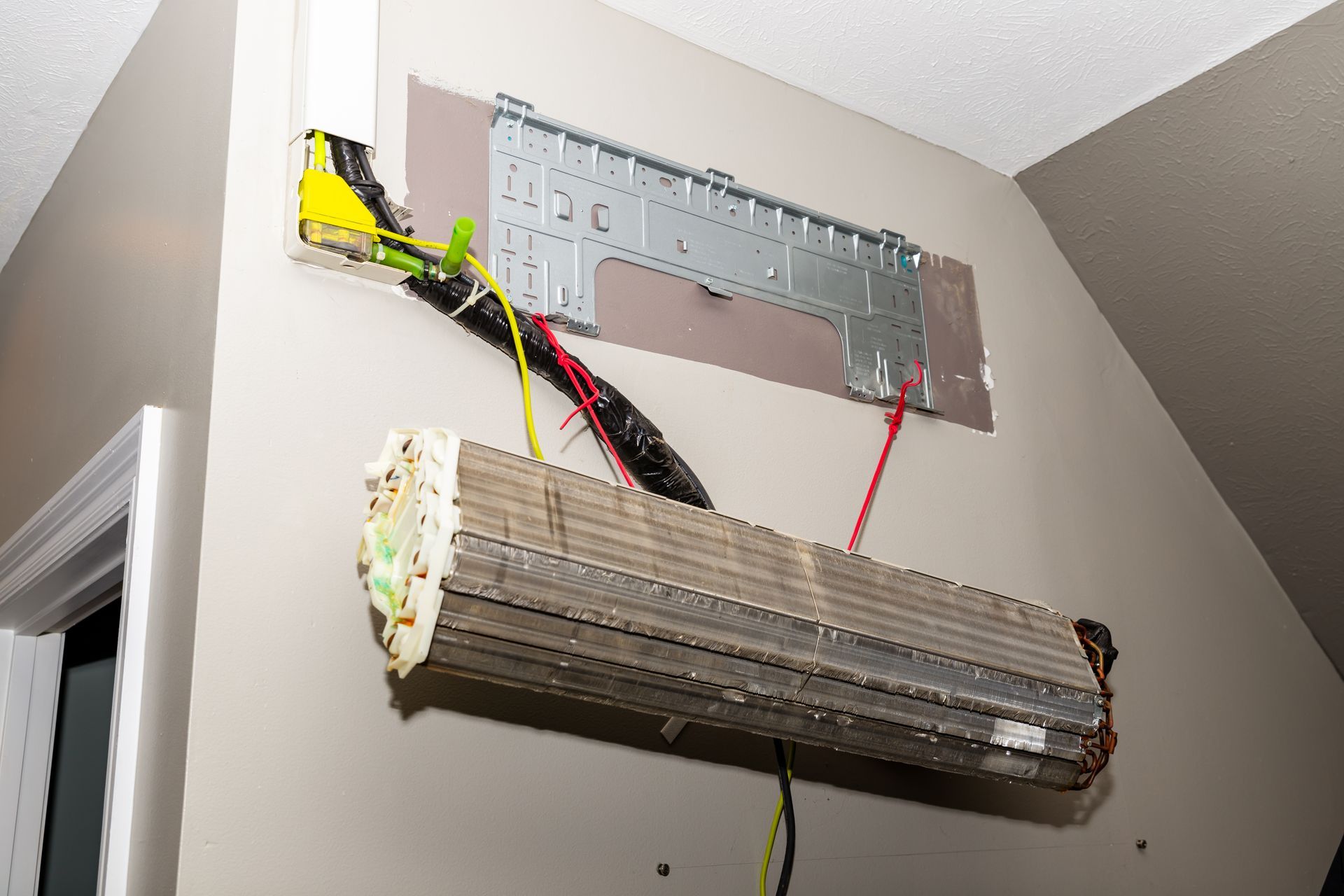 Broken fluorescent light fixture hanging from a ceiling with exposed wiring and a detached cover panel