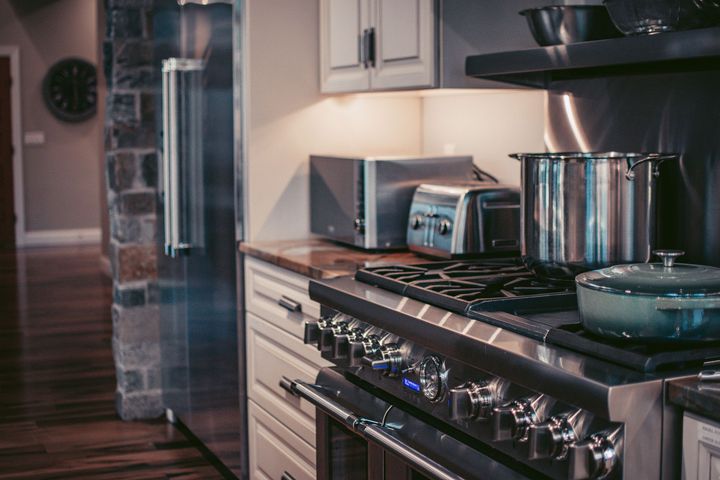 Modern kitchen with stainless steel stove, pots, toaster, and refrigerator near a hardwood floor