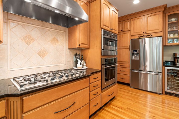 Modern kitchen with stainless steel appliances, wood cabinets, granite counters, and hardwood floors
