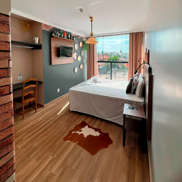 Um quarto de hotel com uma cama king size e um tapete no chão Hotel Barra Bonita