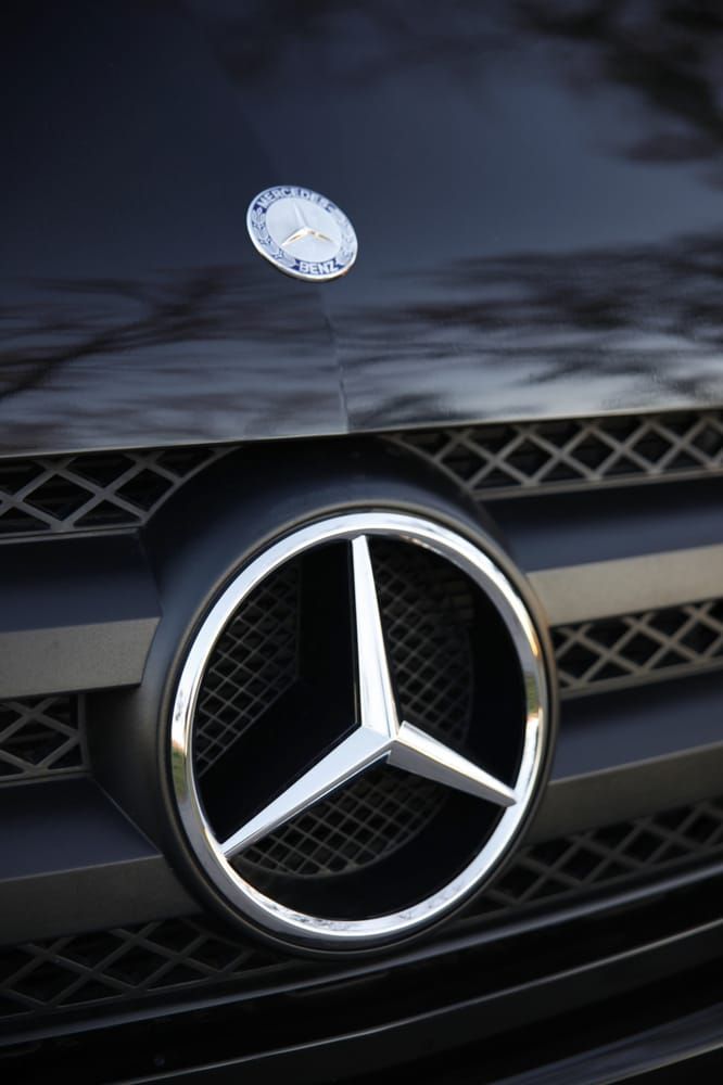 Close-up of a Mercedes-Benz hood ornament and front grille on a dark car