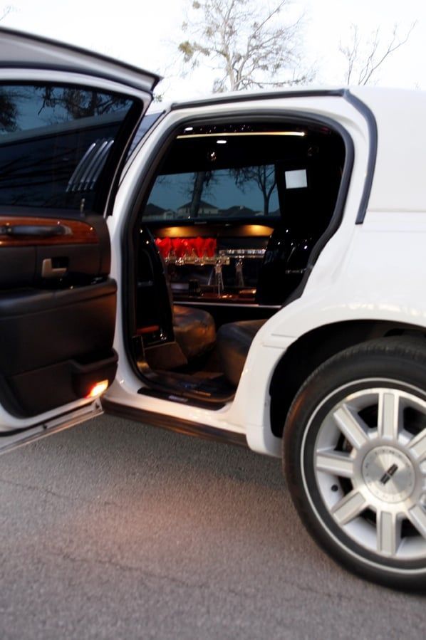Open car door revealing a lit luxury car interior at dusk on a roadside