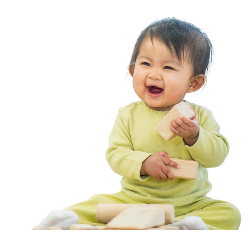 Happy baby with dark hair, wearing a light green outfit, playing with wooden blocks and laughing.