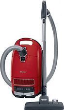 A red vacuum cleaner with a hose attached to it on a white background.