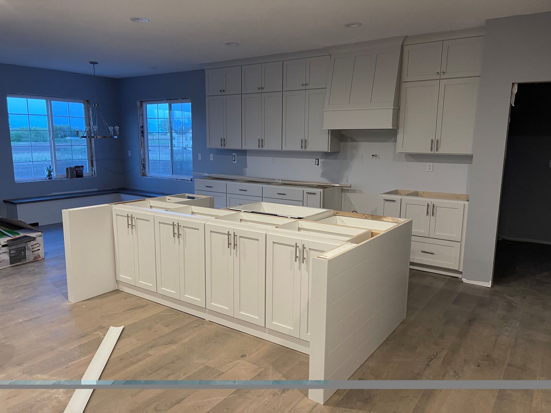Bright open-concept living room and kitchen with gray sofa, dining table, and breakfast bar in a modern home