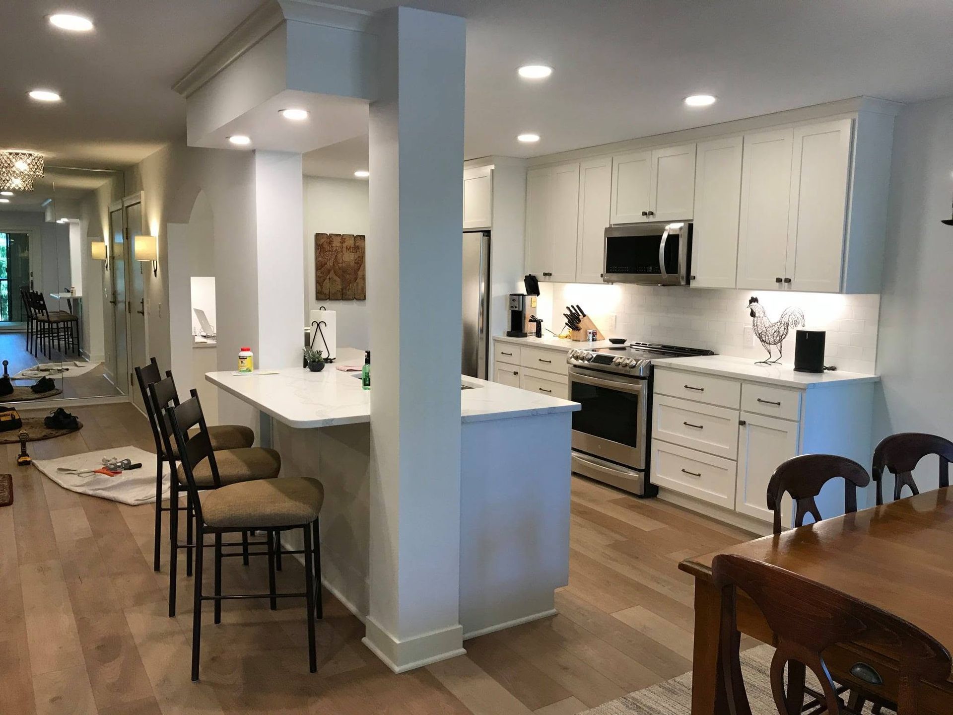 Bright open kitchen and dining area with white cabinets, island seating, and wood floors
