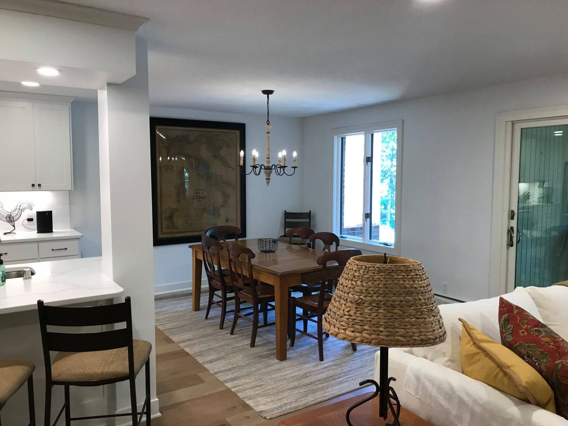 Open dining room with wooden table, chairs, rug, chandelier, and adjacent kitchen