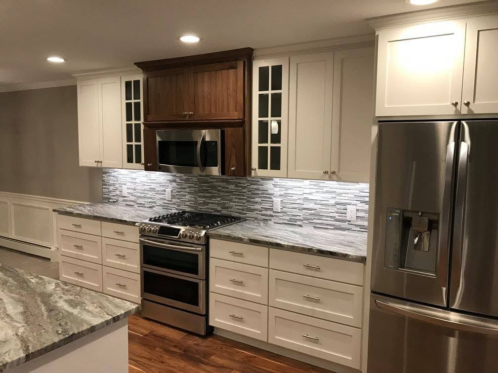 Modern kitchen with white and wood cabinets, stainless steel appliances, and granite countertops.