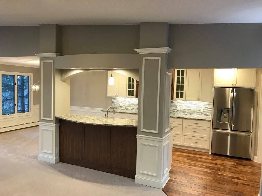 Open kitchen with island, white cabinets, stainless steel fridge, and wood floors