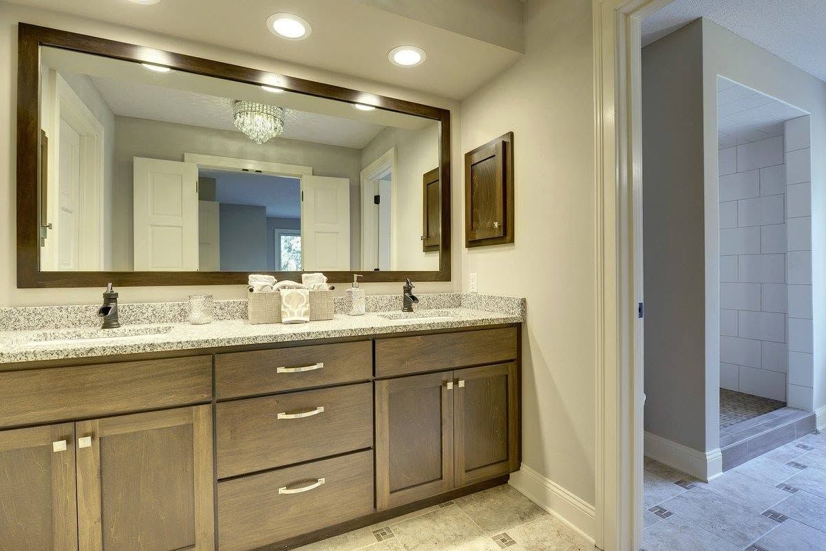 Modern bathroom vanity with granite countertop, large mirror, and doorway to tiled shower area