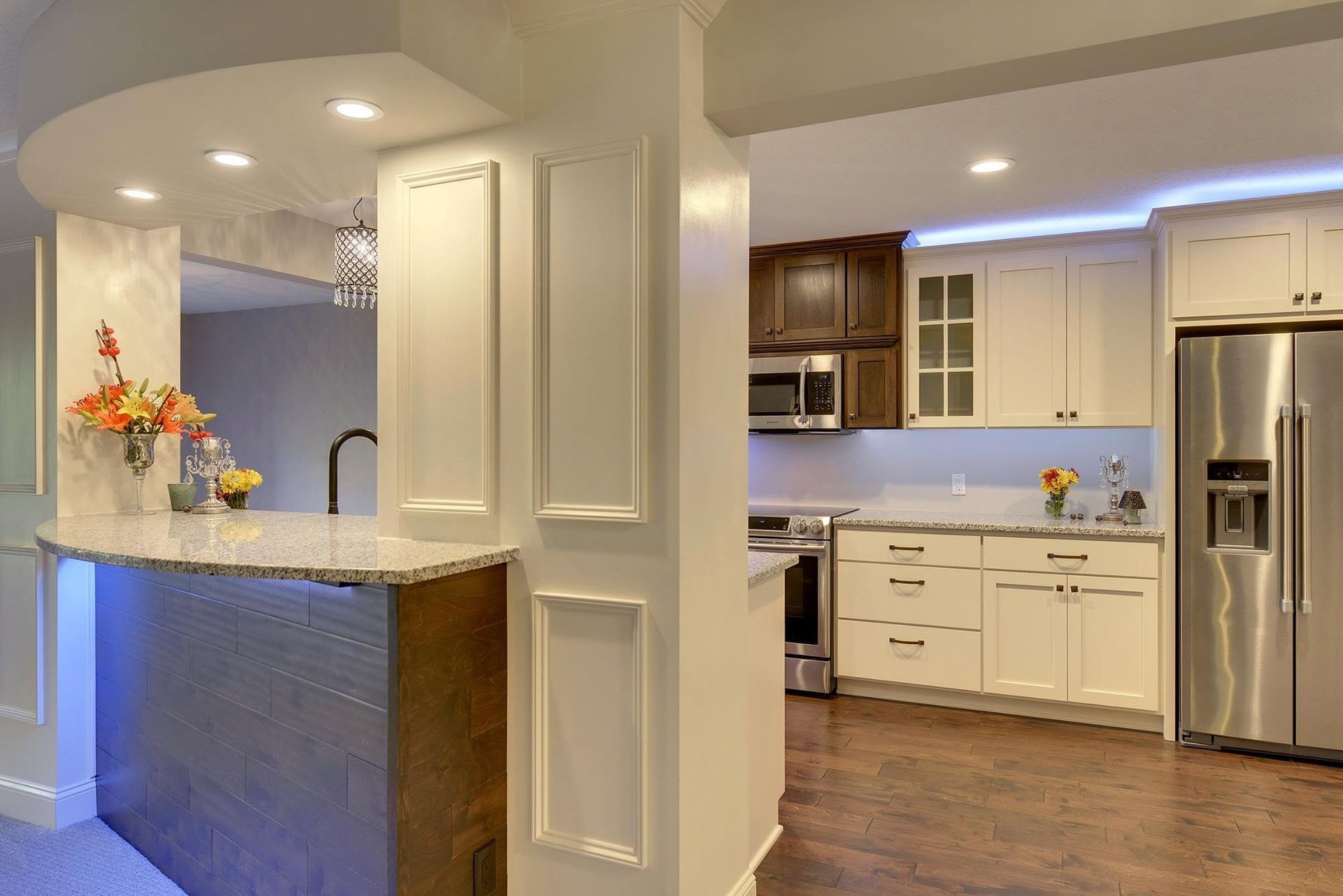 Modern kitchen with white cabinets, stainless steel fridge, granite counter, and adjacent breakfast bar