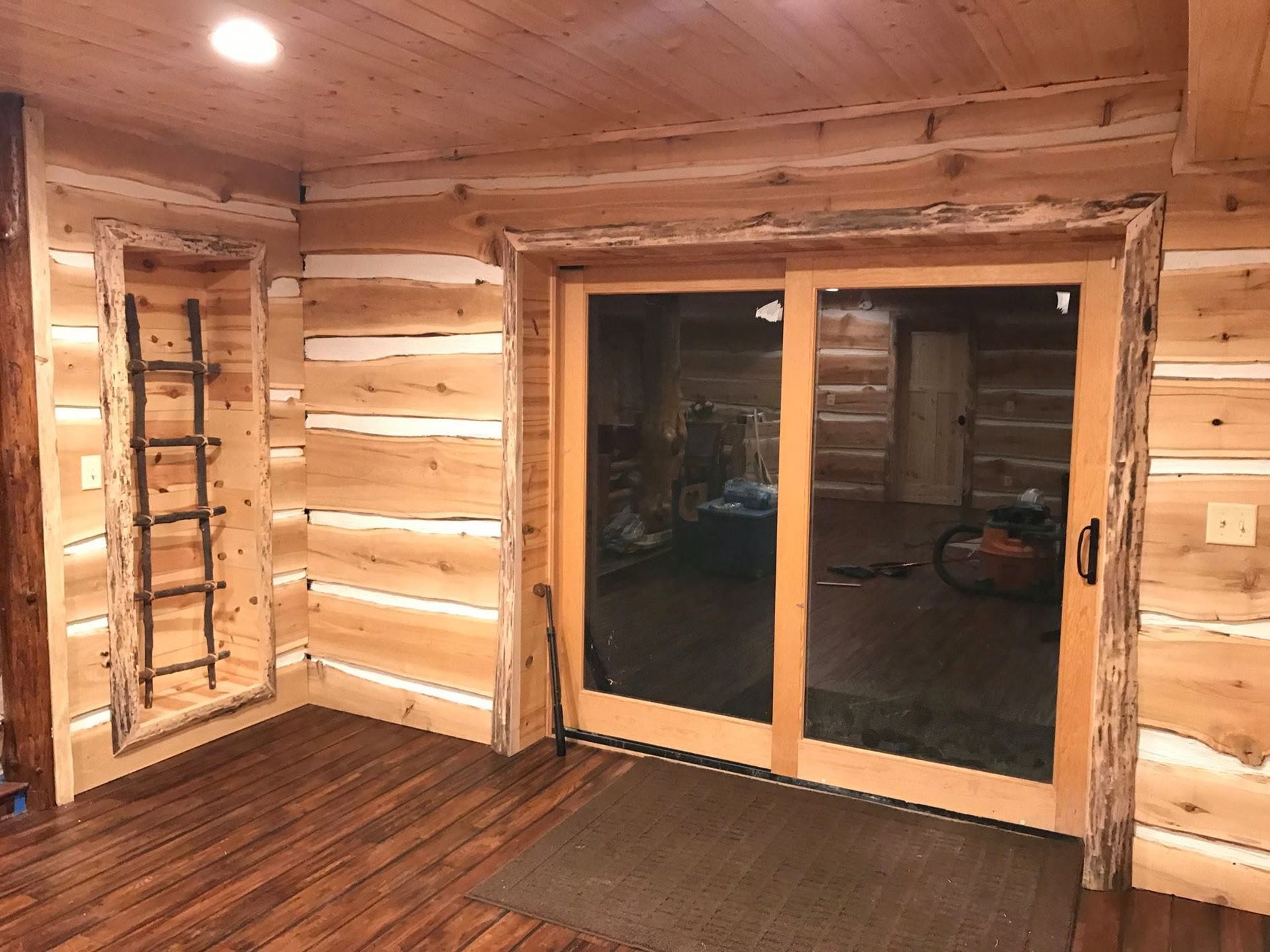 Wood-paneled room with large sliding glass doors, a window, and a dark floor mat.