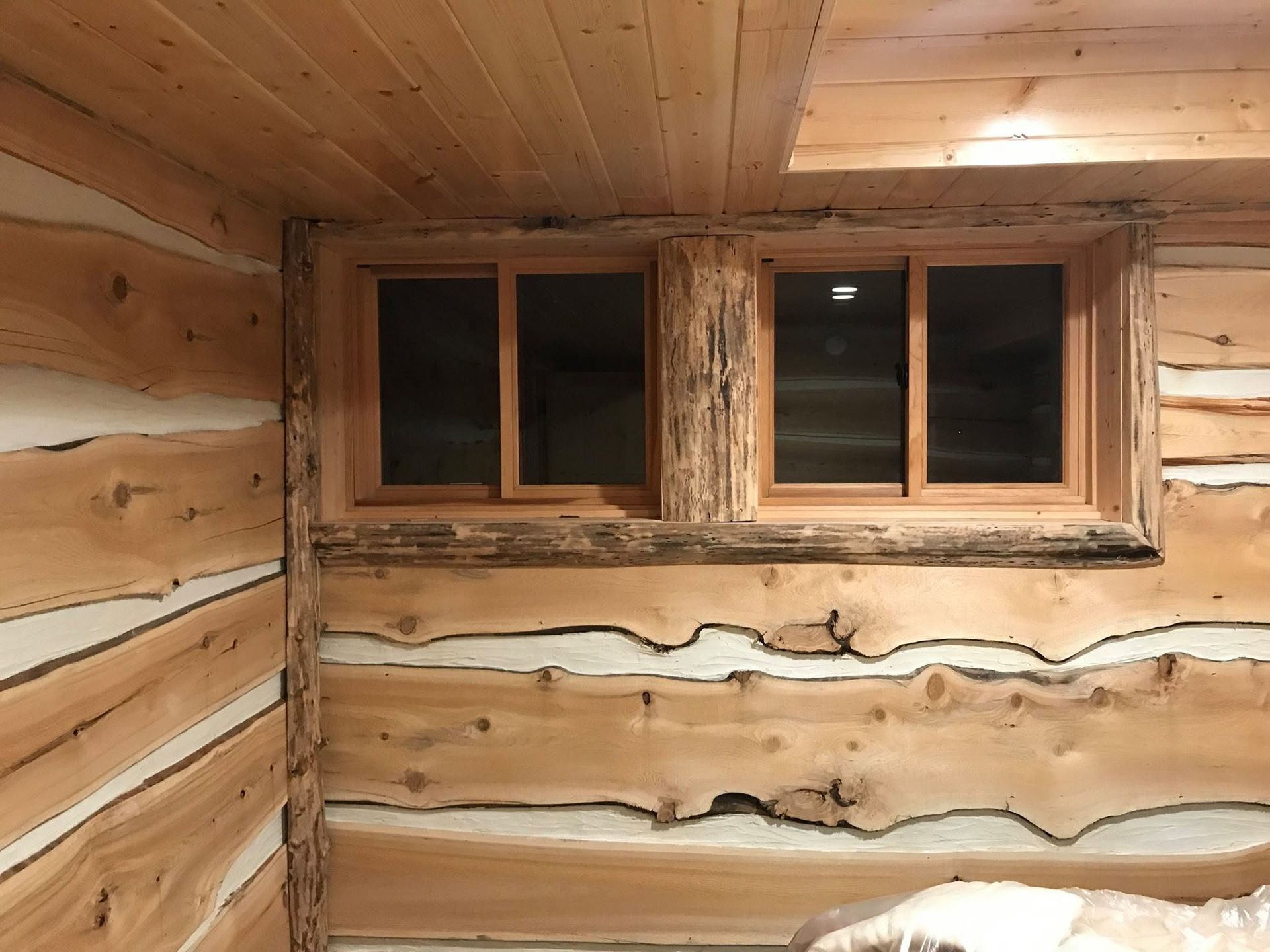 Rustic log cabin interior wall with a small four-pane wooden window.
