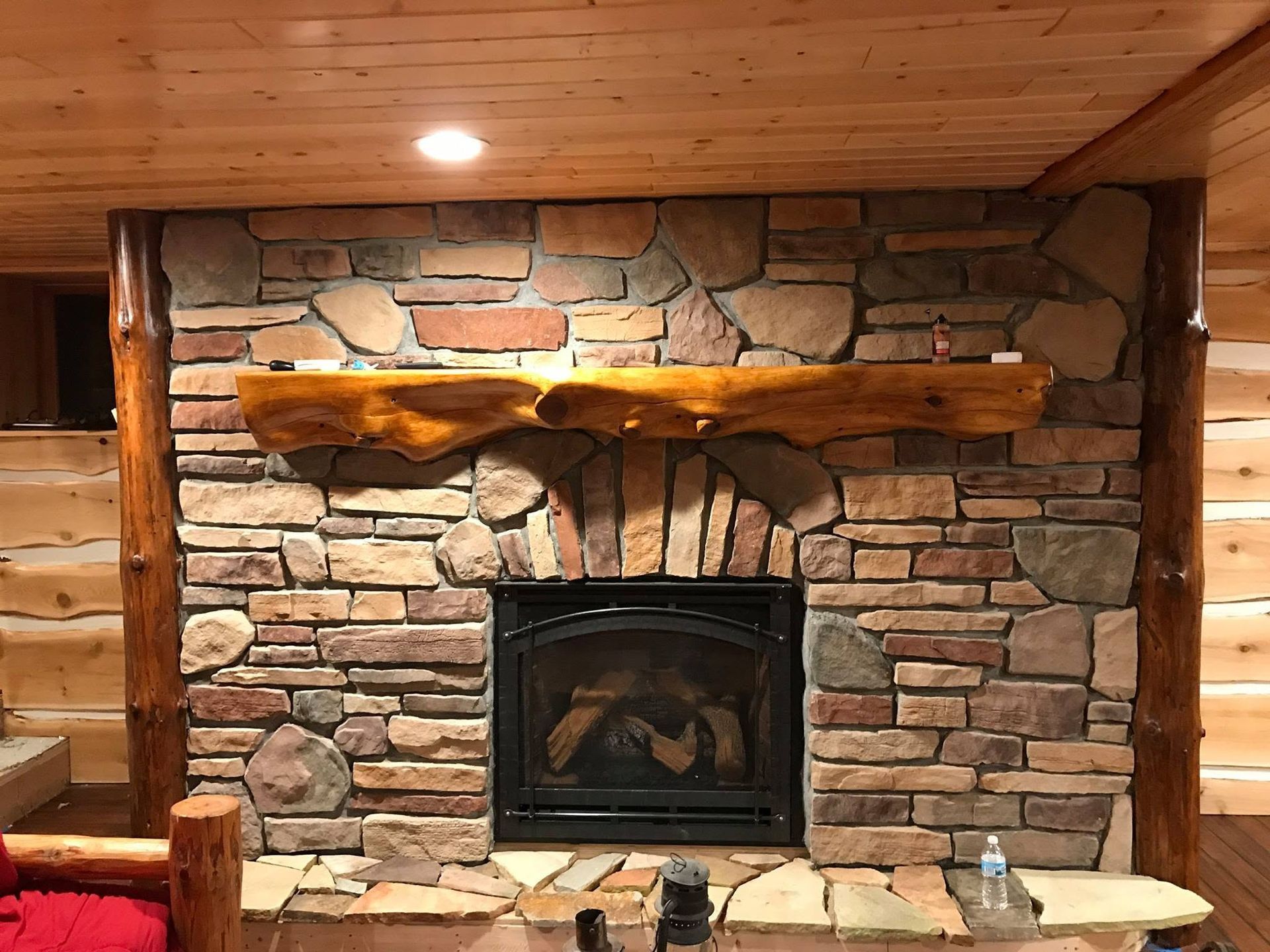 Rustic stone fireplace with wooden mantel in a cozy cabin interior