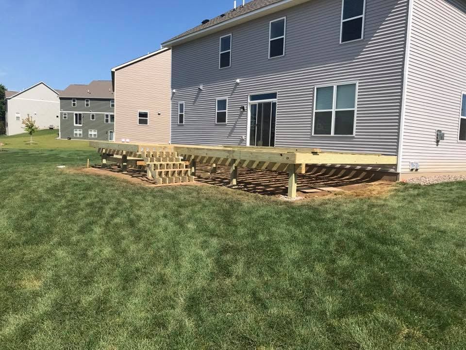 Backyard deck under construction behind a beige two-story townhouse