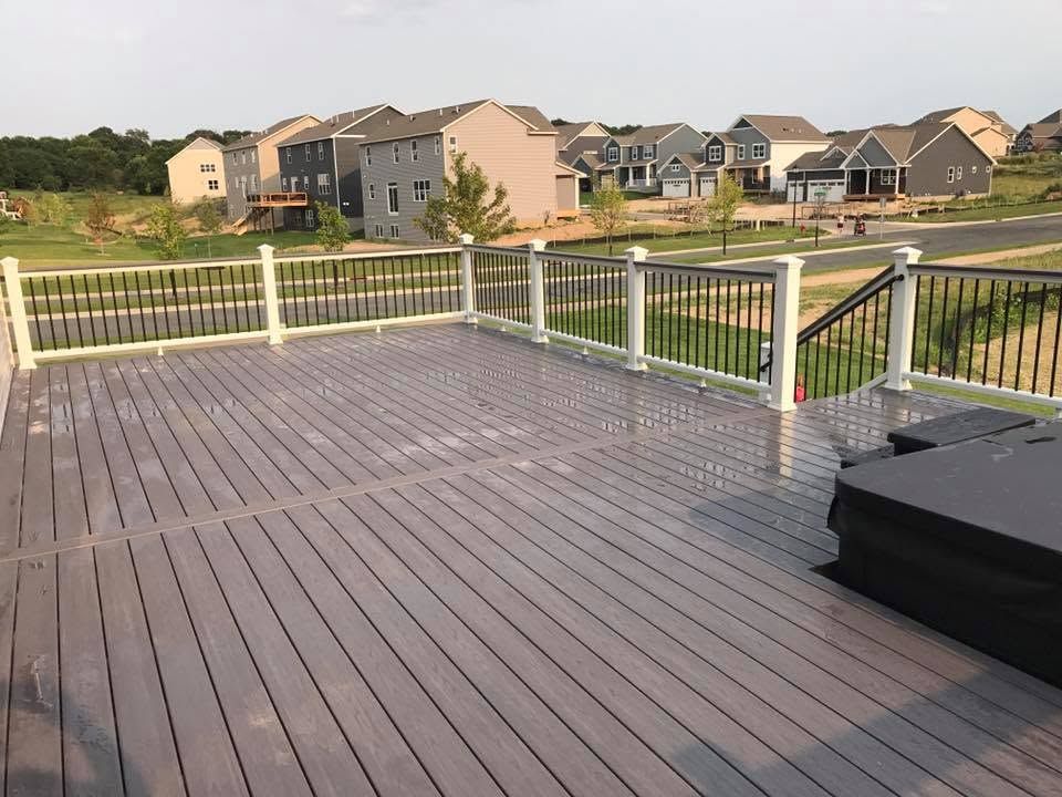 Back deck with gray boards and white railing overlooking suburban homes at sunset
