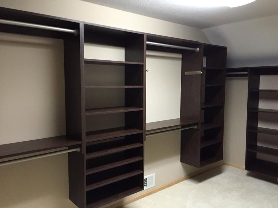 Empty dark-brown built-in closet shelving along a wall in a room.