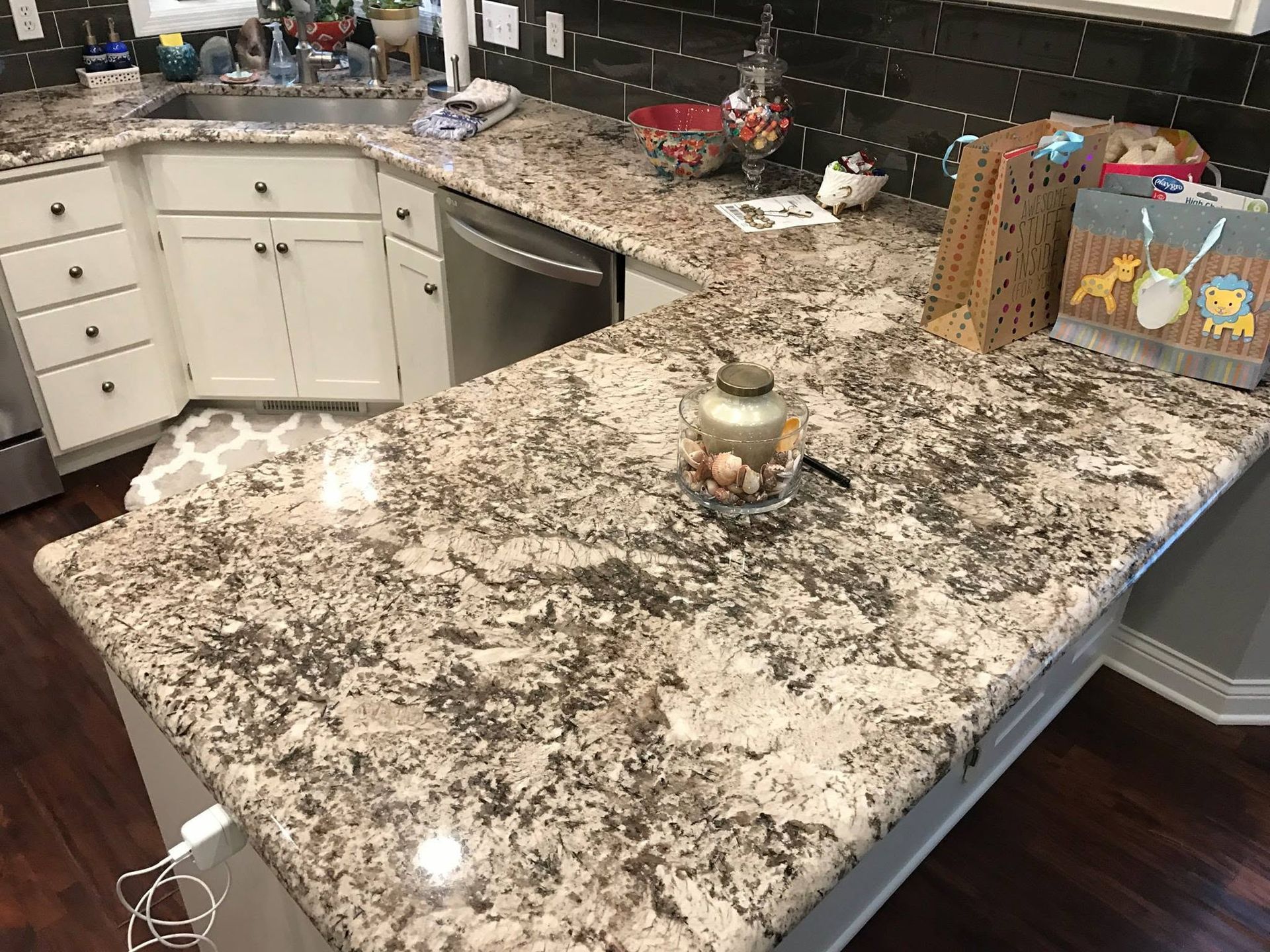 Granite kitchen island with a small decorative candle centerpiece and white cabinets in the background