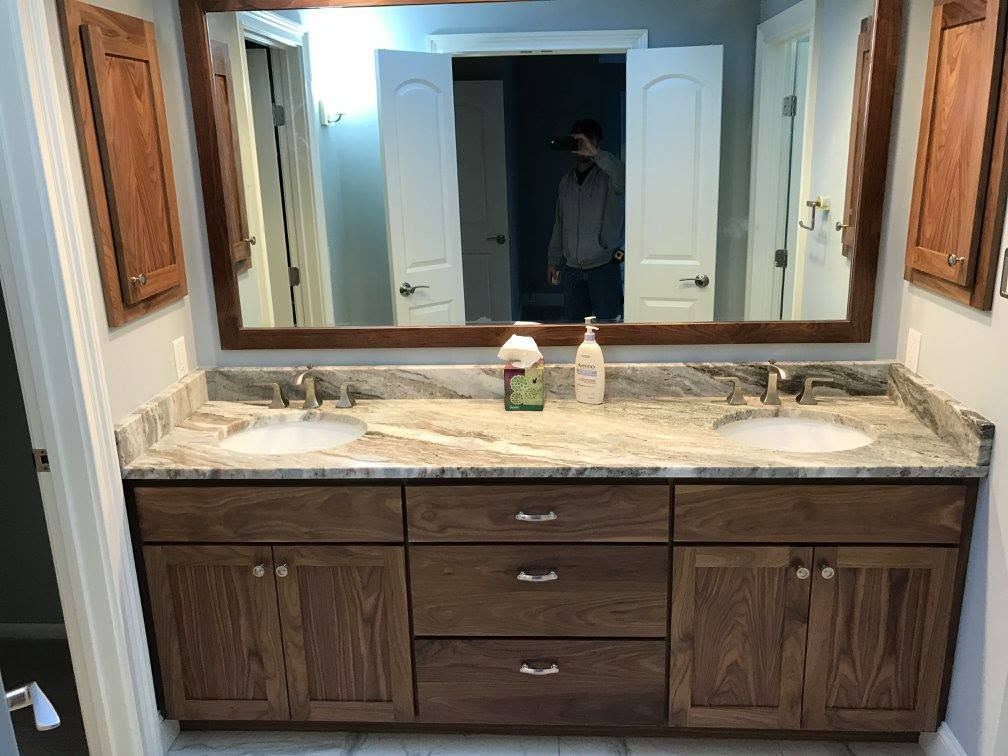 Bathroom vanity with double sinks, granite countertop, and large mirror above dark wood cabinets.