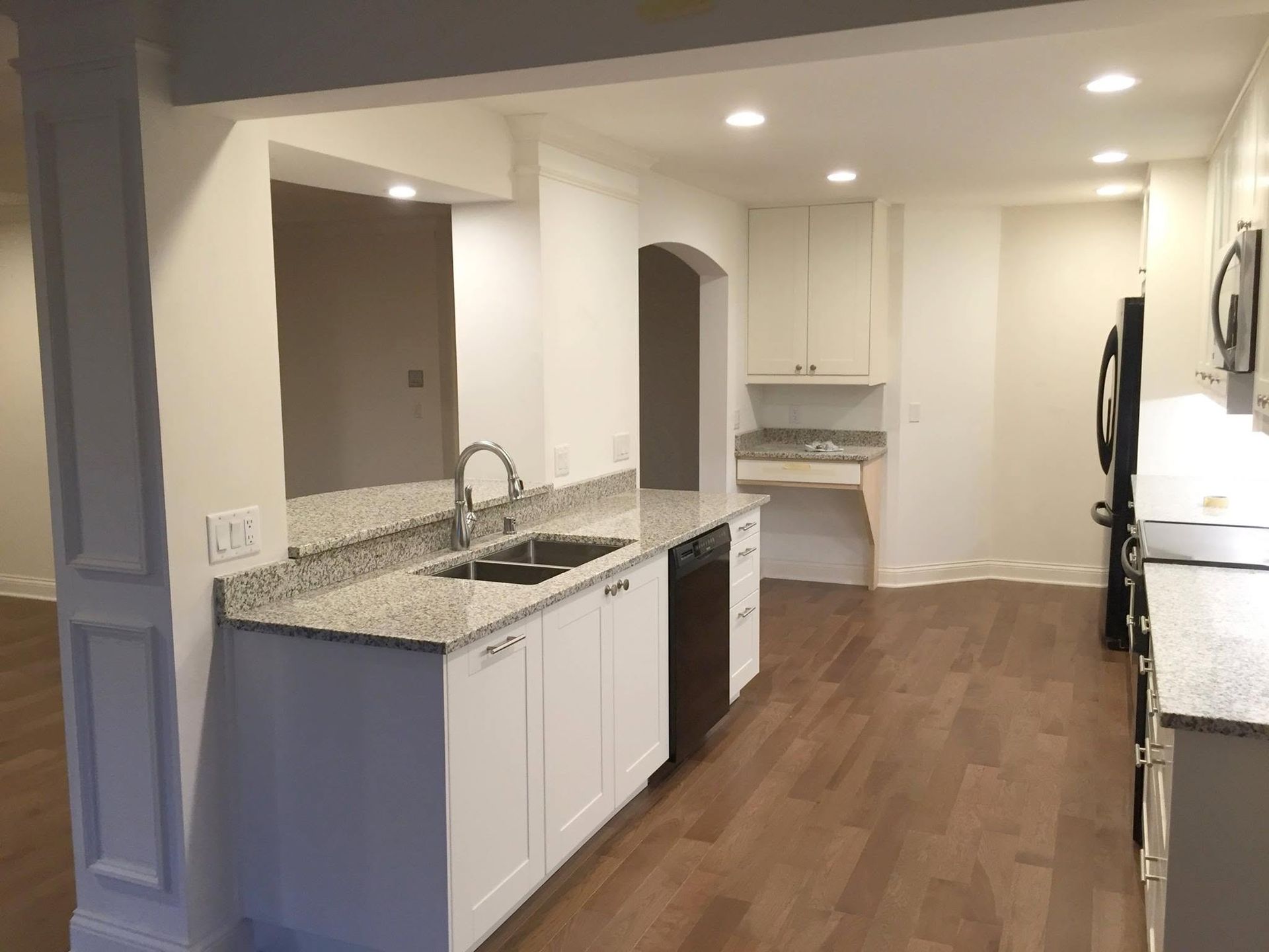 Bright modern kitchen with white cabinets, granite countertops, and hardwood floors