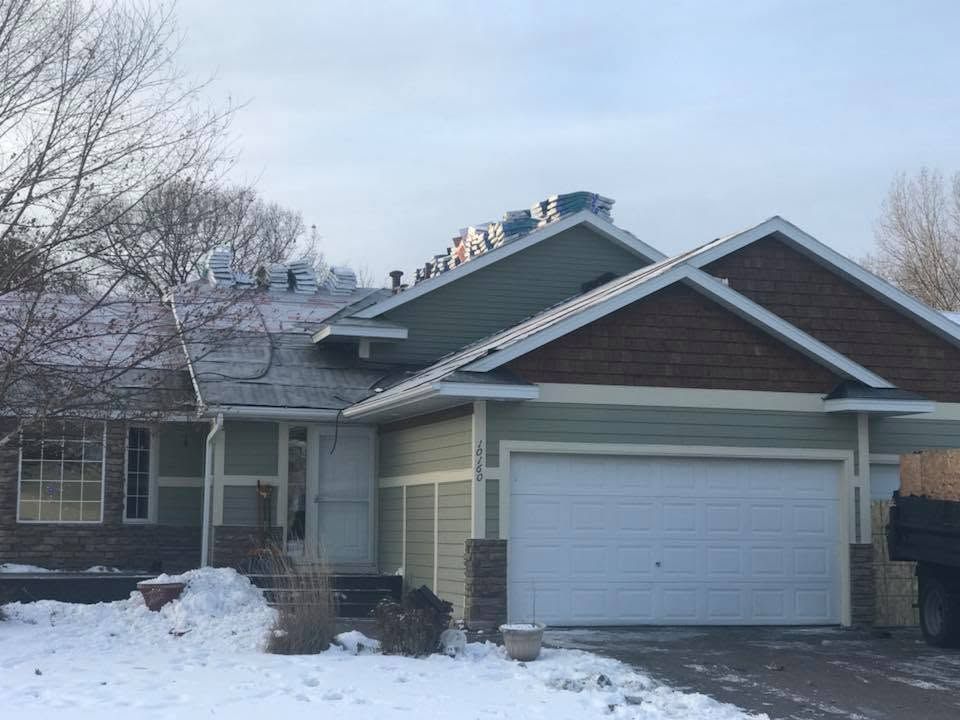 Snow-covered suburban house with a two-car garage and bare trees in front
