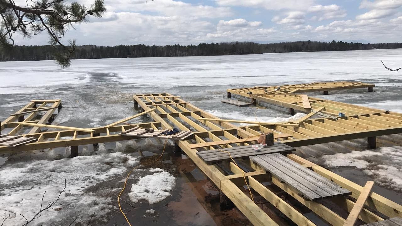 Broken wooden dock on a frozen lake under a cloudy sky