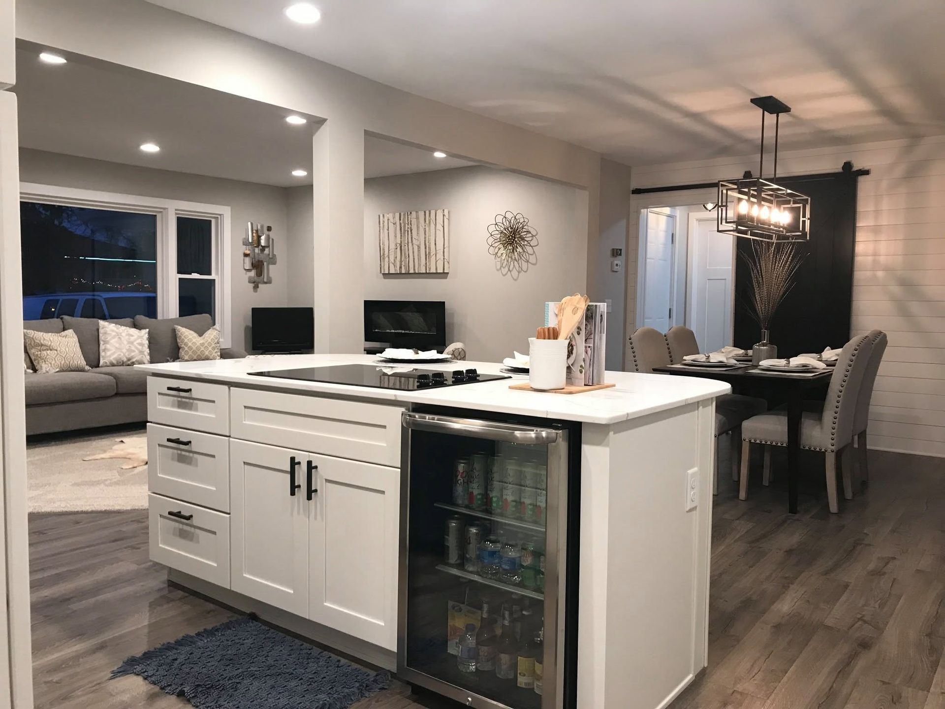 Modern kitchen with white island, stainless wine cooler, and open dining and living area