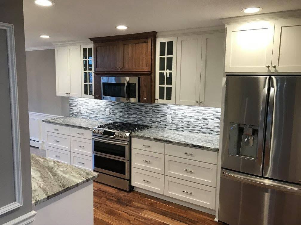 Modern kitchen with white cabinets, stainless steel appliances, and marble countertops