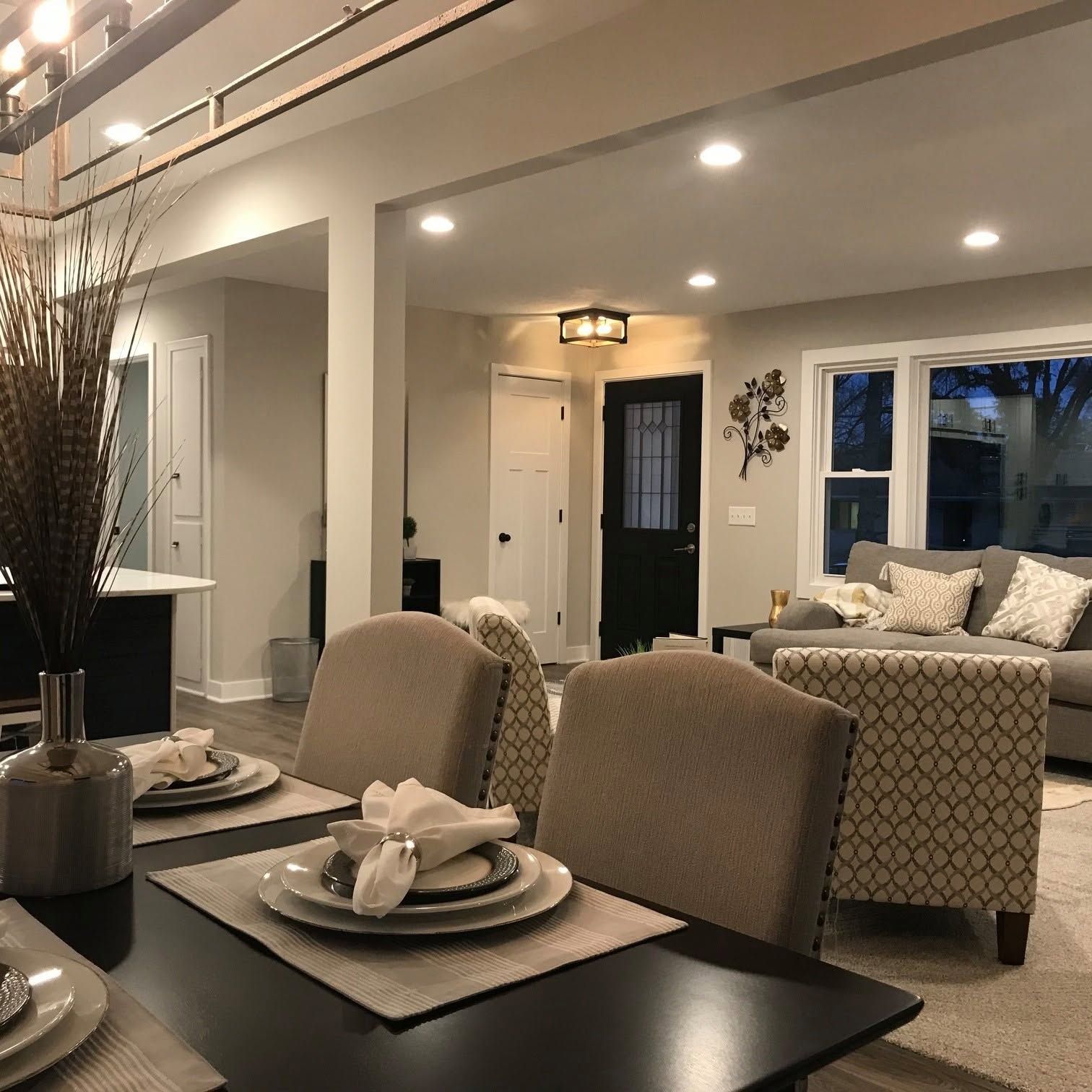Open-concept living and dining room with beige seating, dark table, and soft recessed lighting