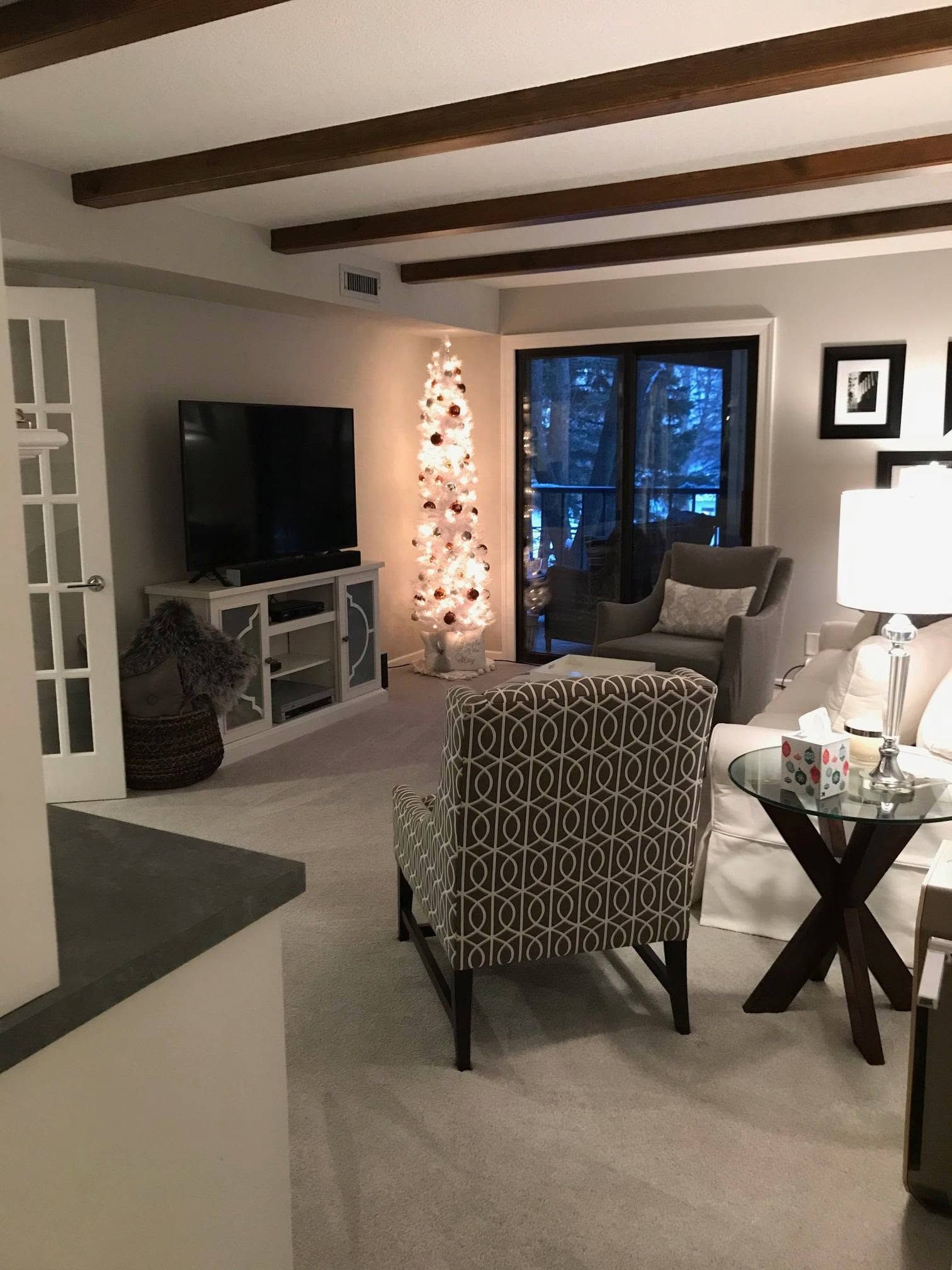 Cozy living room with TV, armchair, lamp, fireplace, and glass doors at night