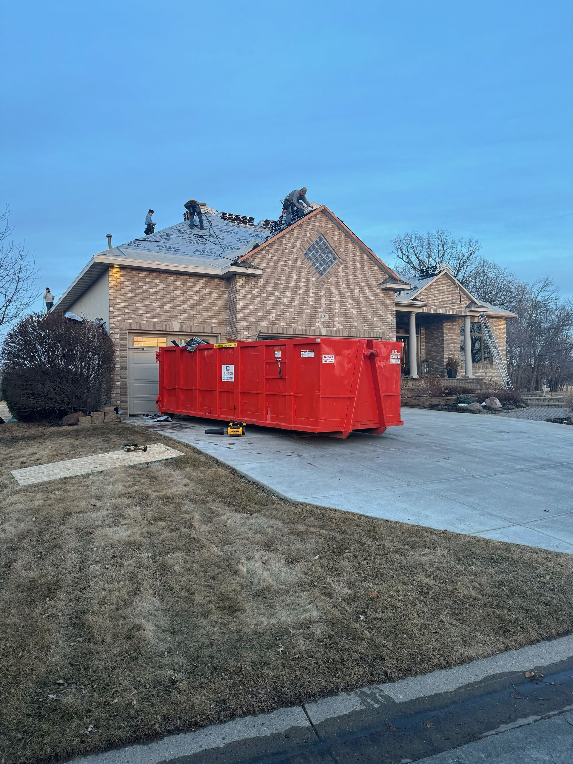 Suburban two-story house with stone accents, two cars in the driveway, and a manicured front lawn