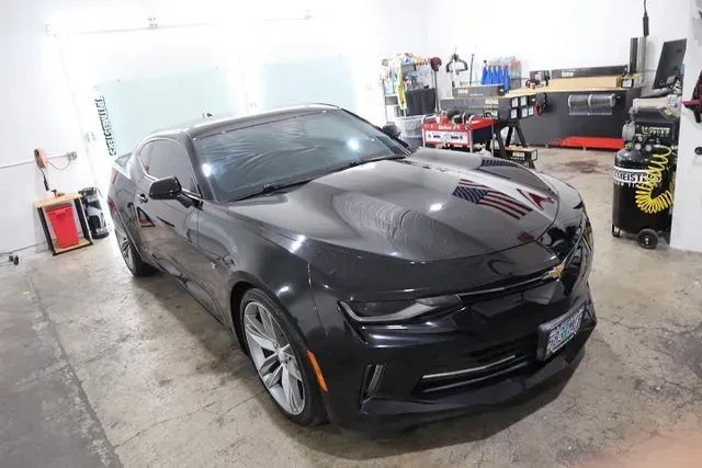 A black chevrolet camaro is parked in a garage.