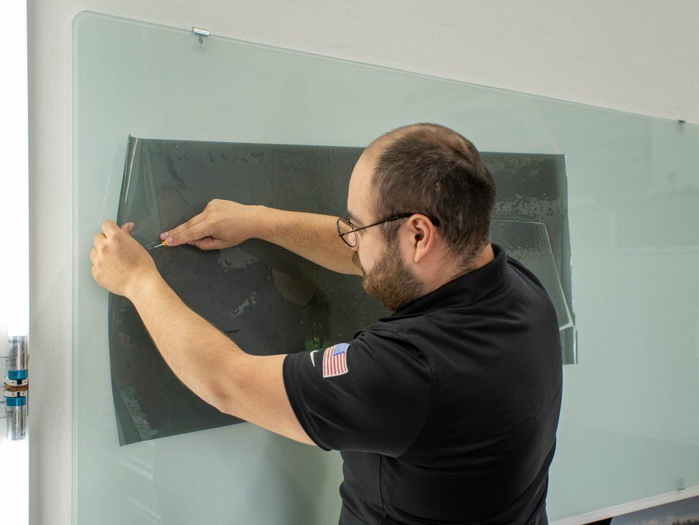 A man is putting a piece of film on a glass wall.