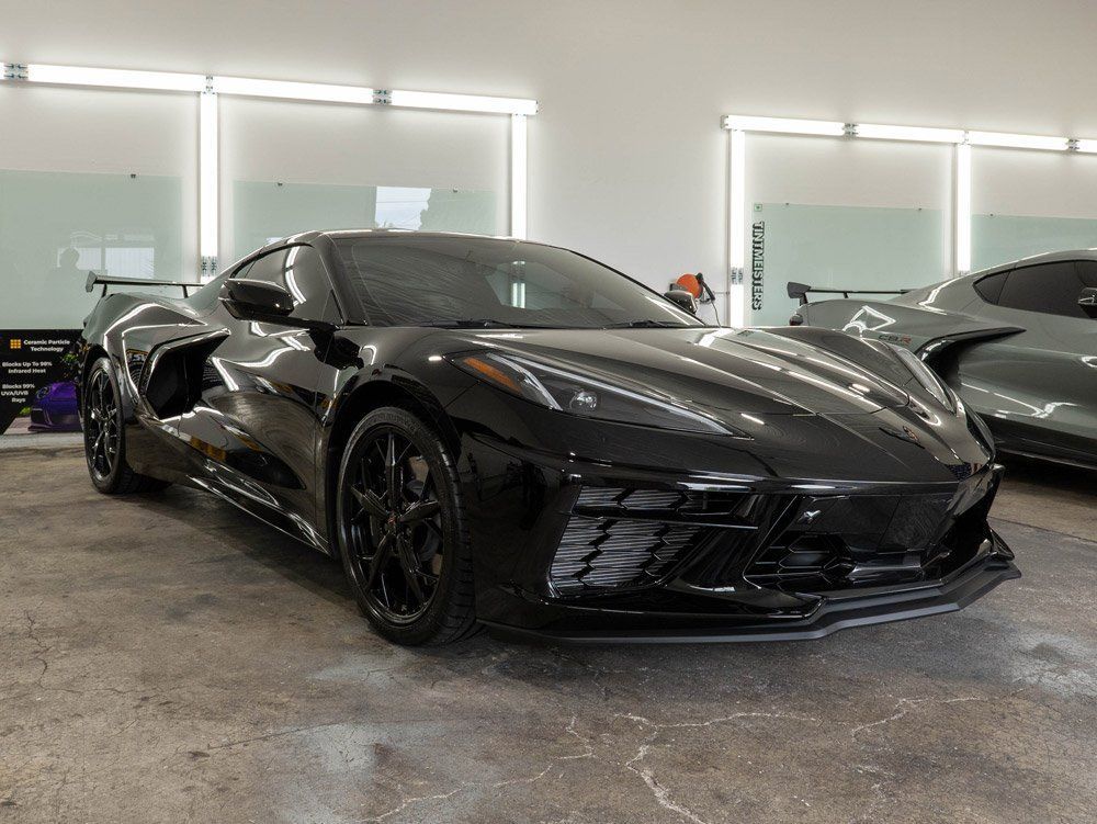A black corvette is parked in a garage.