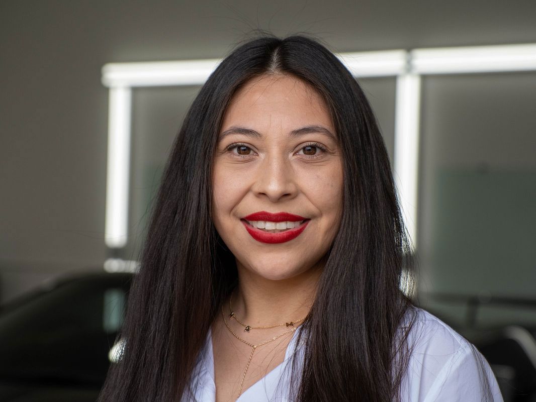 A woman with long hair and red lipstick is smiling for the camera.