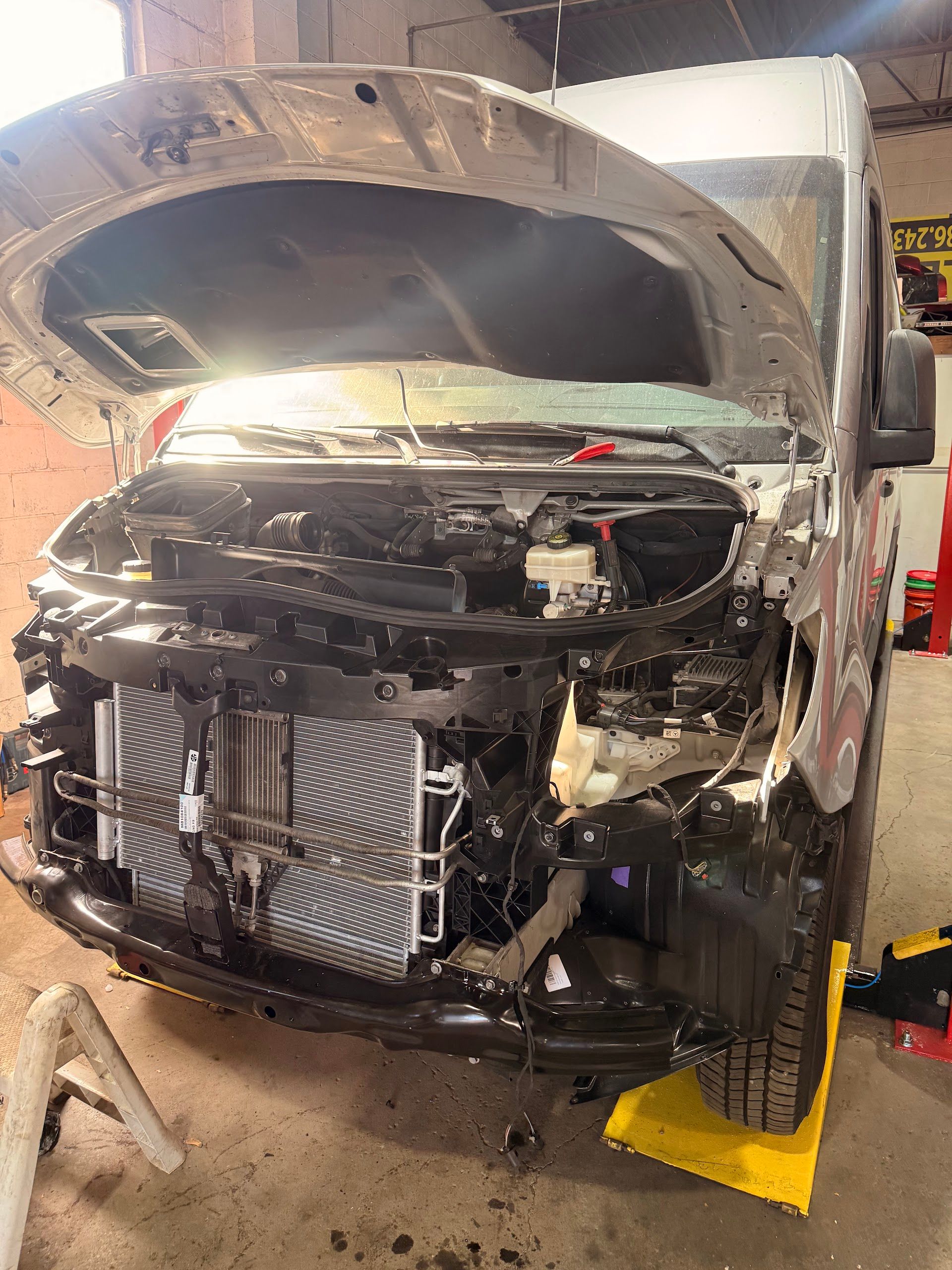 A silver van with its hood open and front bumper removed, revealing the radiator, parked inside an auto repair shop. | Christian's Auto Repair