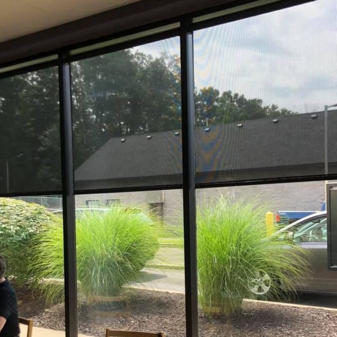 A window with a white blind on it and a clock on the window sill.
