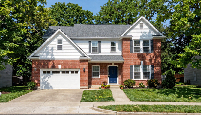 Two-story suburban house with white siding, red brick, attached garage, and a front lawn.