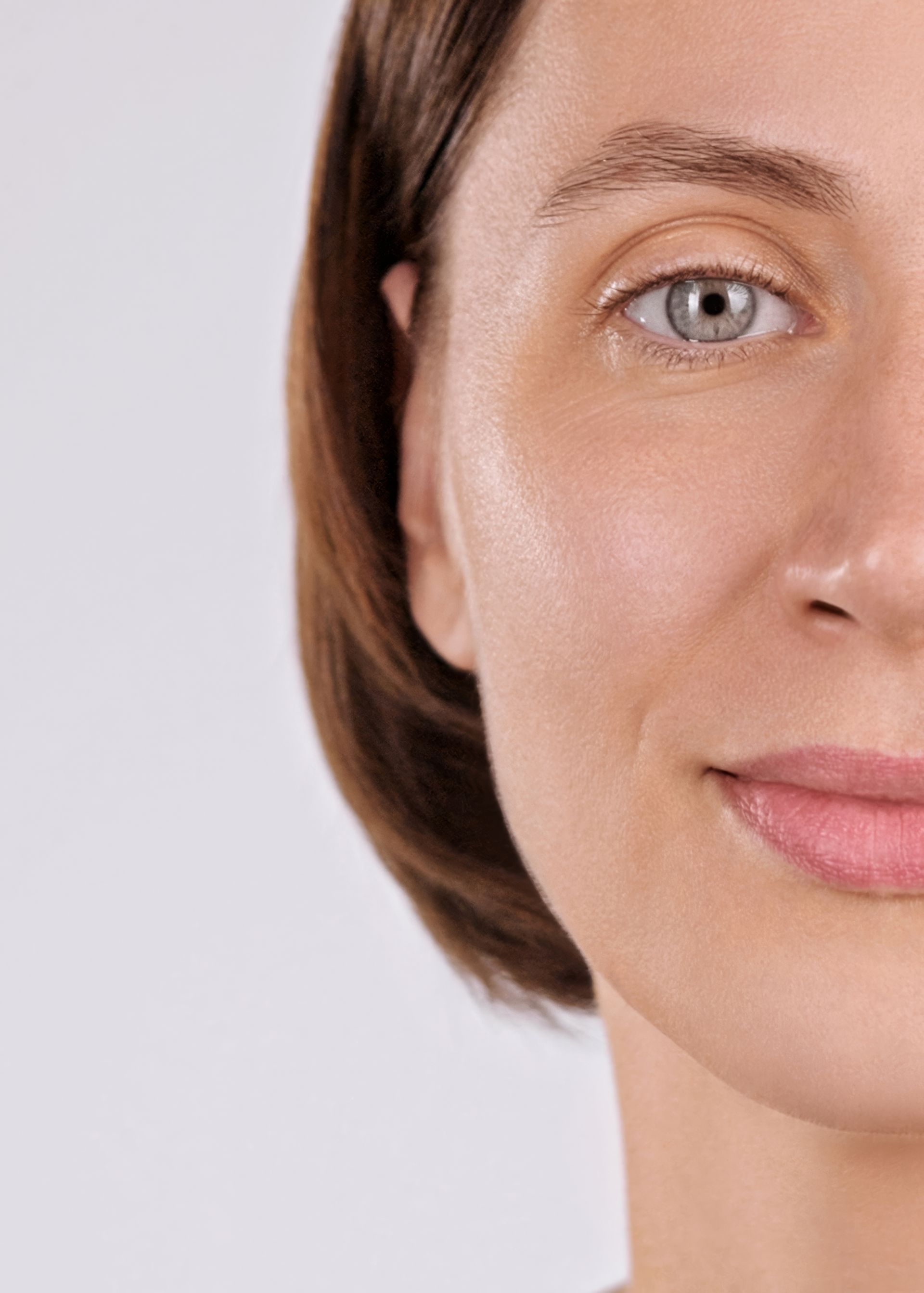Close-up of a smiling face with short brown hair against a light background