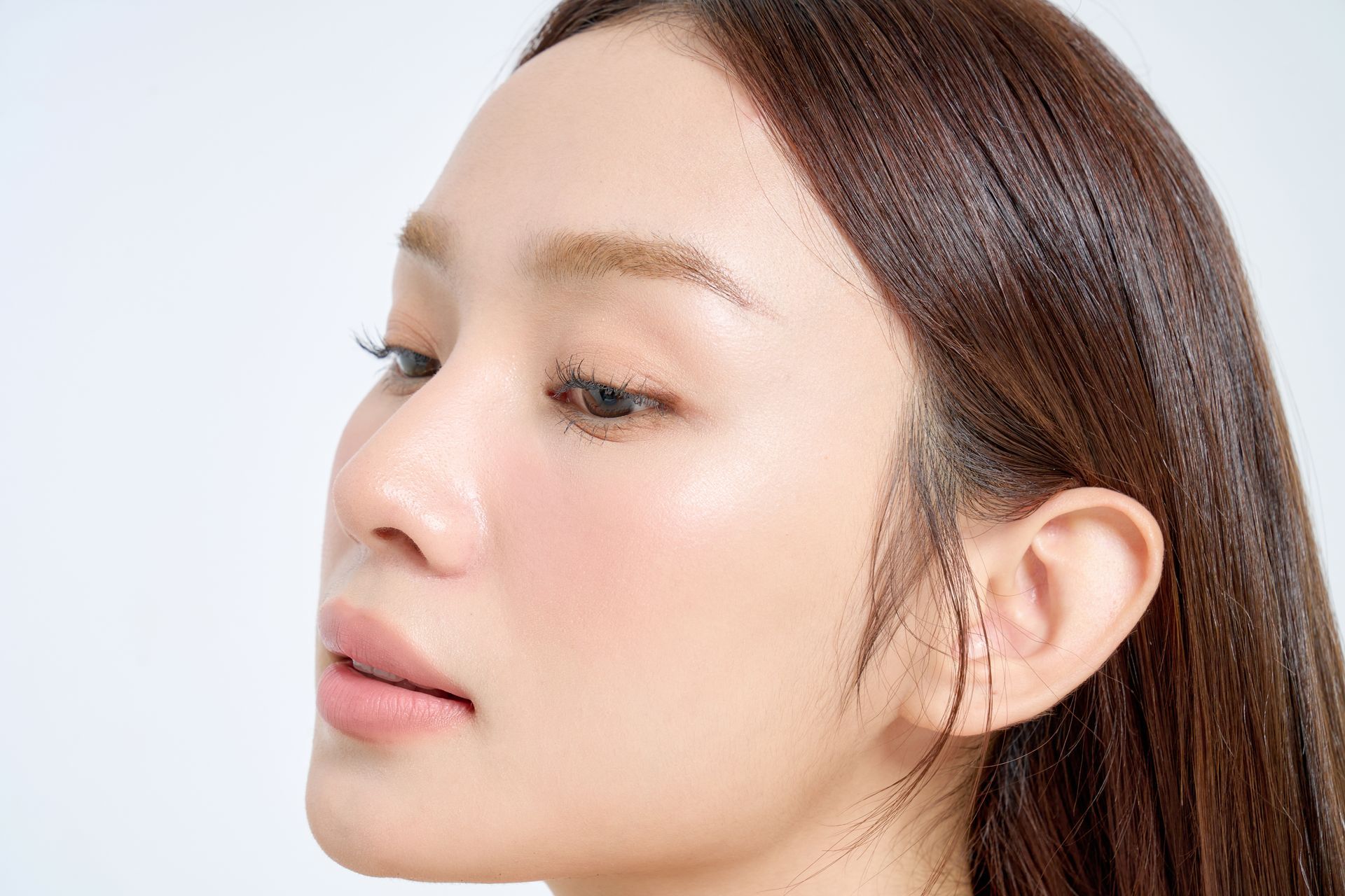 Close-up profile of a woman with long brown hair against a white background