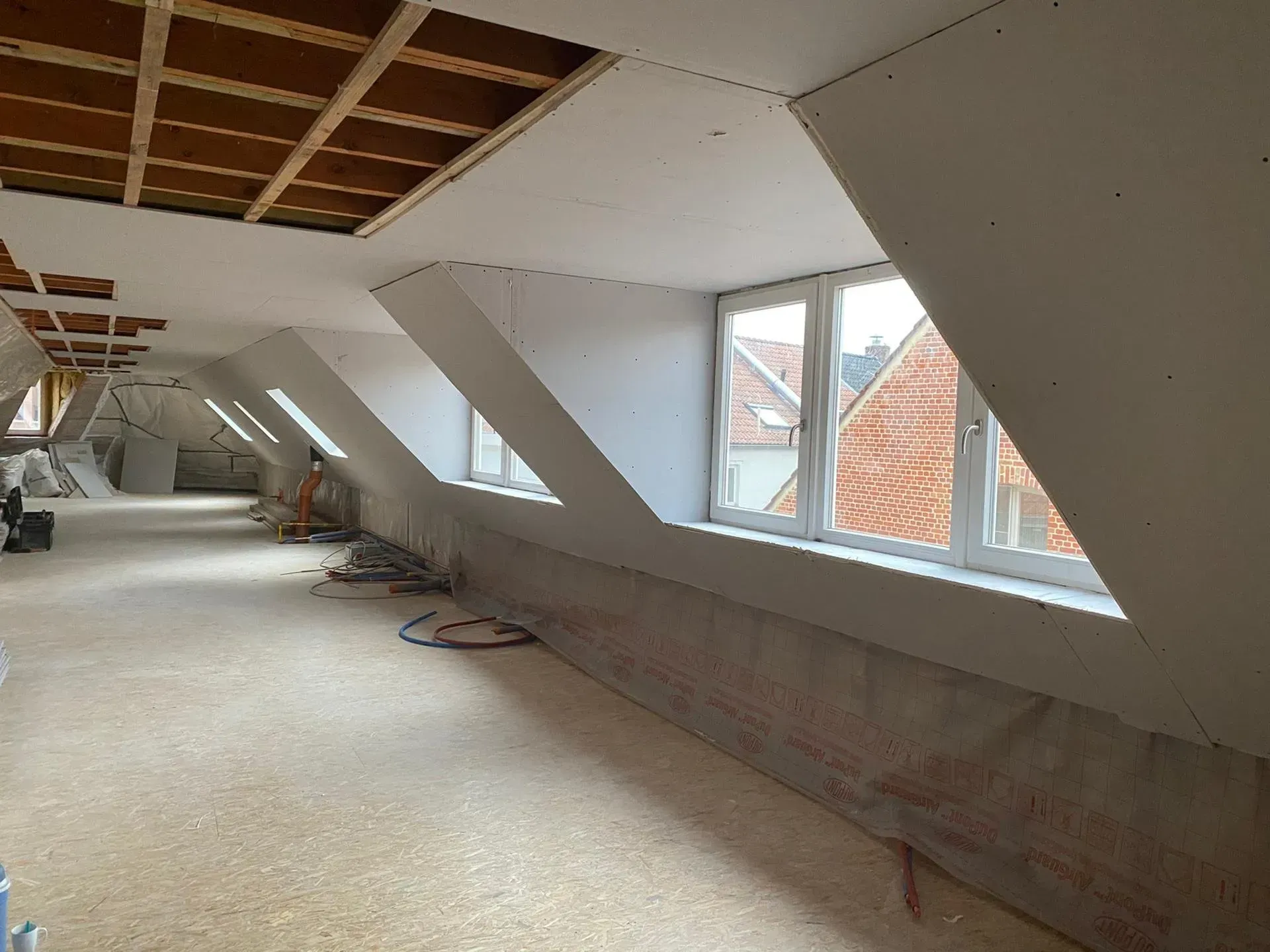 Interieurconstructie met schuine ramen en zichtbare plafondbalken.