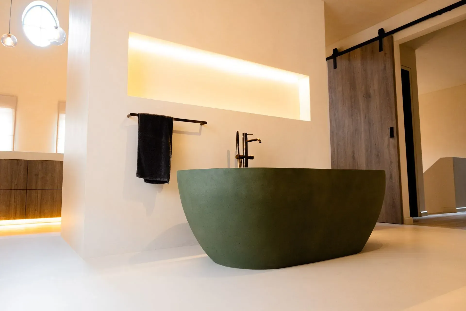 Groen bad in een moderne badkamer met houten deur en een plankje met sfeerverlichting.