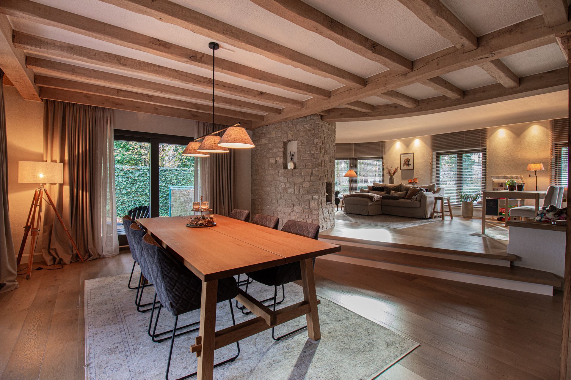 Eetkamer met houten tafel, stoelen, open naar de woonkamer, natuurlijk licht en neutrale kleuren.